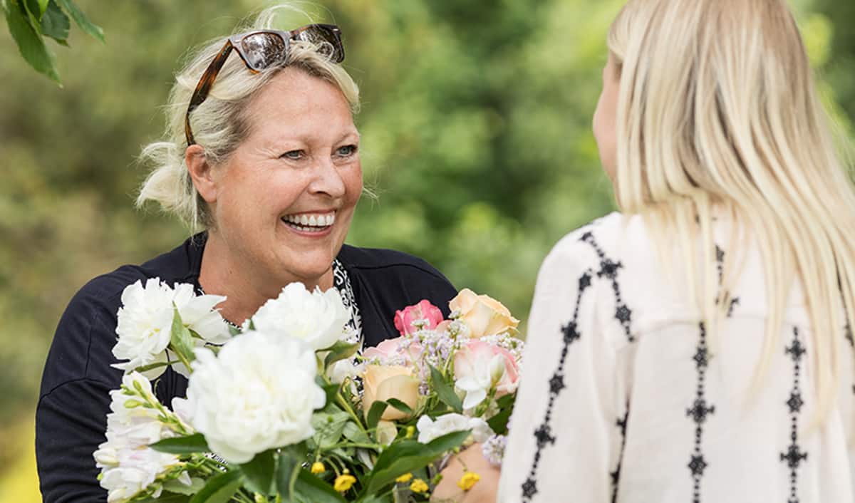 Frau bekommt Blumen von einer anderen Frau und lacht