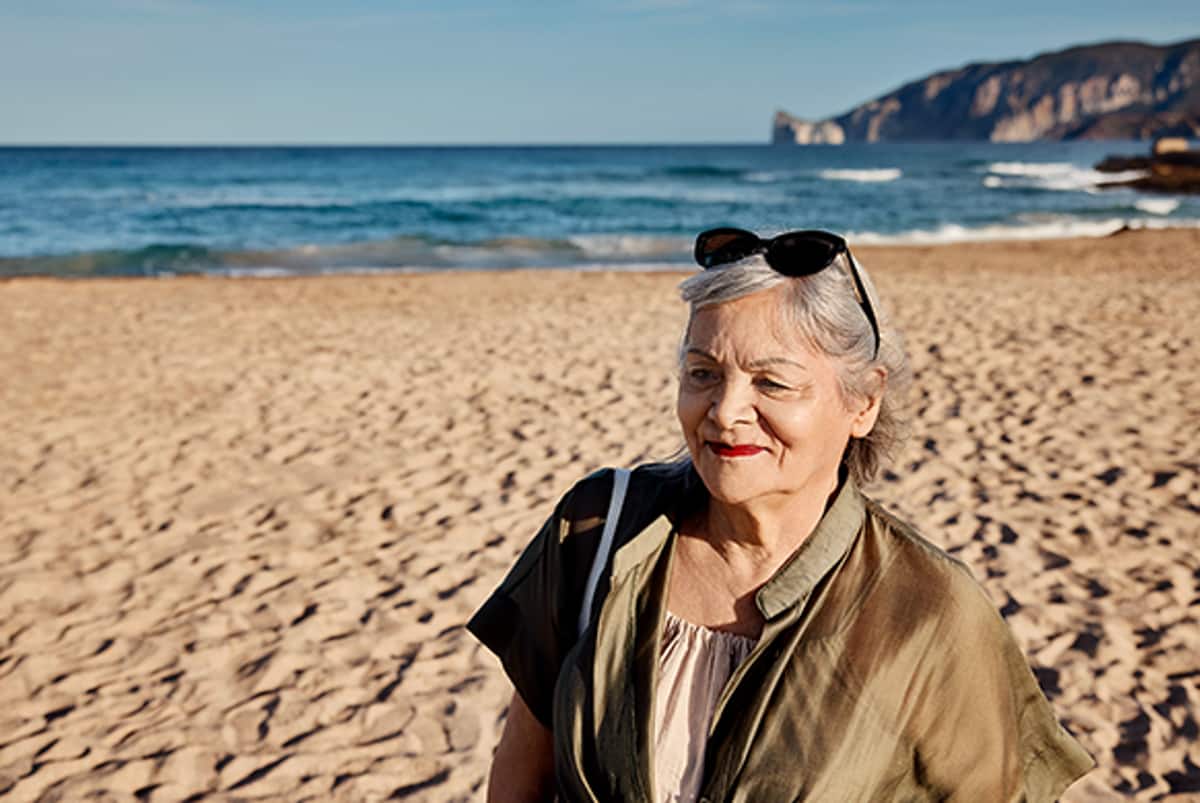 Frau am Strand mit Sonnenbrille auf dem Kopf